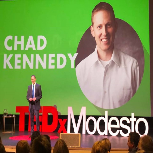 Chad Kennedy in a suit on stage at the TEDx talk